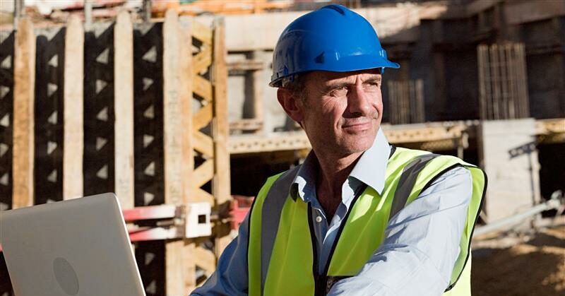 mature man using-laptop on construction site